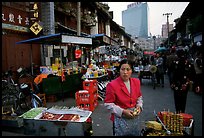 Street market in an old alley of wooden buildings, with a high rise in the background. Kunming, Yunnan, China