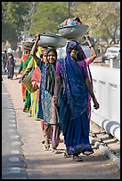 Women walking in line carrying baskets on heads. Khajuraho, Madhya Pradesh, India