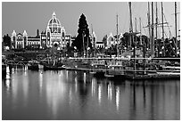 Boats in inner harbor with a trail of lights and parliament building lights. Victoria, British Columbia, Canada (black and white)