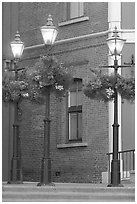Street lamps with flower baskets and brick wall. Victoria, British Columbia, Canada (black and white)