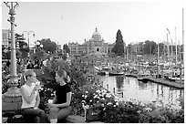 Women drinking coffee at the Inner Harbour, sunset. Victoria, British Columbia, Canada (black and white)
