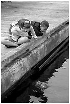 Kidds looking at a harbor seal, Fisherman's wharf. Victoria, British Columbia, Canada ( black and white)