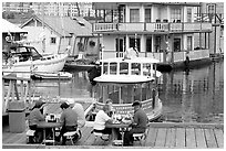 People eating fish and chips on deck,  Fisherman's wharf. Victoria, British Columbia, Canada ( black and white)