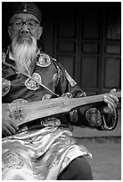 Elderly musician playing the a traditional guitar. Baisha, Yunnan, China ( black and white)