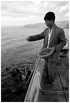 Cormorant fisherman feeds small fish to his birds as a prize for catching large fish. Dali, Yunnan, China ( black and white)