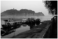 Boats along the river with cliffs in the background. Leshan, Sichuan, China (black and white)