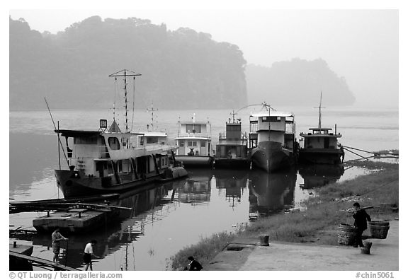 Boats along the river with misty cliffs in the background. Leshan, Sichuan, China (black and white)