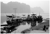 Boats along the river with misty cliffs in the background. Leshan, Sichuan, China (black and white)