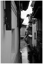 Canal sneaking narrowly between walls. Lijiang, Yunnan, China (black and white)