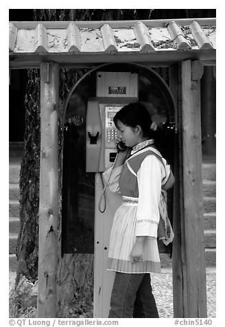 Woman in Naxi dress in a telephone booth. Lijiang, Yunnan, China (black and white)