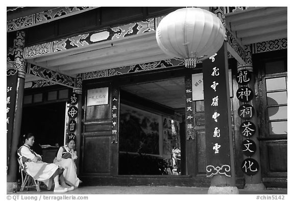 Women sit ouside  the Wufeng Lou (Five Phoenix Hall). Lijiang, Yunnan, China (black and white)