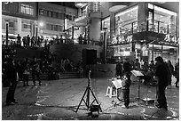 Tourists watch girl singing at night near the pier, Shueishe Village. Sun Moon Lake, Taiwan ( black and white)