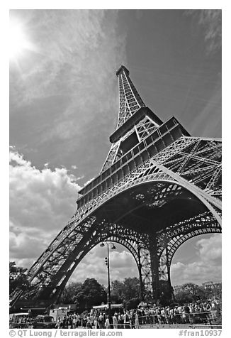 Eiffel tower and sun with crowds at base. Paris, France