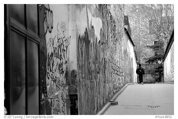 Boy in side alley with graffiti on walls. Paris, France