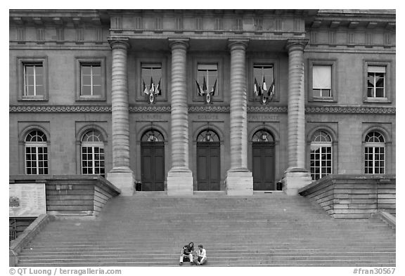 Two visitors sitting on the stairs of the Palais de Justice. Paris, France (black and white)
