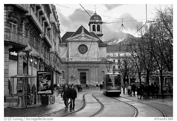 Street with people walking tramway and church Grenoble France black and