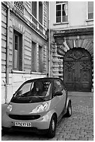 Tiny car on coblestone pavement in front of historic house. Lyon, France (black and white)