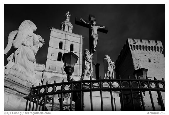 Cross with Christ, statues, and towers, evening light. Avignon, Provence, France (black and white)