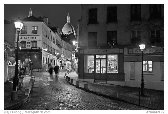 Cobblestone street, lamps, and Sacre-Coeur basilica by night, Montmartre. Paris, France