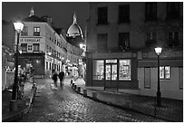 Cobblestone street, lamps, and Sacre-Coeur basilica by night, Montmartre. Paris, France (black and white)