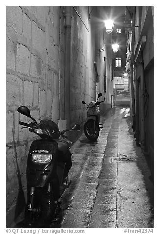 Motorcycles parked in narrow alley at night. Quartier Latin, Paris, France (black and white)