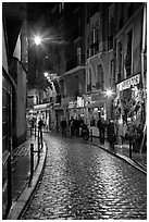 Cobblestone street with restaurants by night. Quartier Latin, Paris, France (black and white)