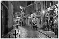 Street with cobblestone pavement and restaurants by night. Quartier Latin, Paris, France (black and white)