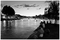 People sitting on tip of Ile de la Cite at sunset. Paris, France ( black and white)