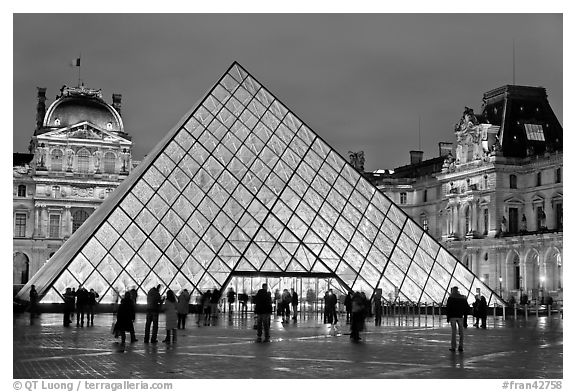 People standing in front of Louvre Pyramid by night. Paris, France