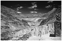 Woman sitting on roof of house in front of mountain landscape, Zanskar, Jammu and Kashmir. India (black and white)
