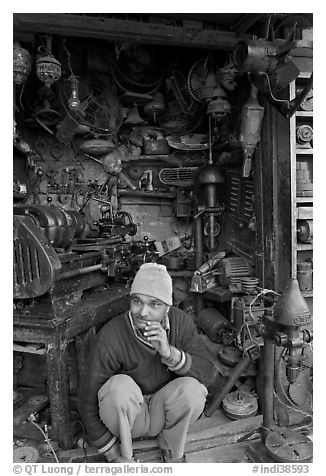 Man sitting in front of machine parts shop, Old Delhi. New Delhi, India (black and white)