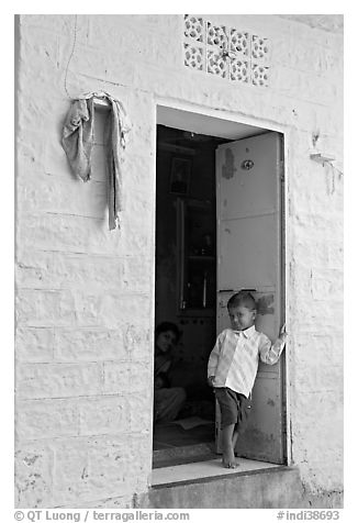 Young boy in doorway of house painted light blue. Jodhpur, Rajasthan, India (black and white)