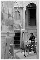 Boy riding a bicycle in a narrow old town street. Jodhpur, Rajasthan, India ( black and white)