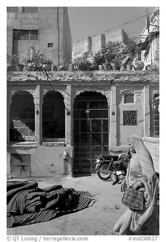 Woman in sari, blue house, and fort in the distance. Jodhpur, Rajasthan, India (black and white)