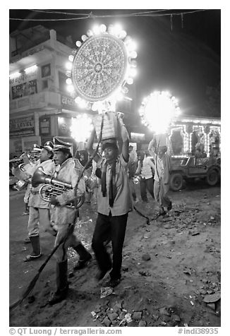 Uniformed musicians and men carrying lights during wedding procession. Varanasi, Uttar Pradesh, India (black and white)