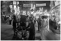 Men pulling generator on bicycle to power lights during wedding procession. Varanasi, Uttar Pradesh, India (black and white)