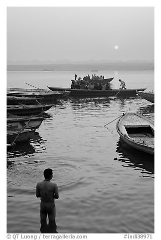 Man standing in Ganga River and boats at sunrise. Varanasi, Uttar Pradesh, India