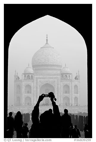 Tourist pointing  digital camera to Maj Mahal, framed by arch of gateway. Agra, Uttar Pradesh, India (black and white)