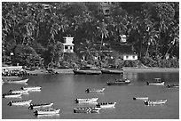 Boats, and palm-tree covered hillside, Dona Paula. Goa, India (black and white)