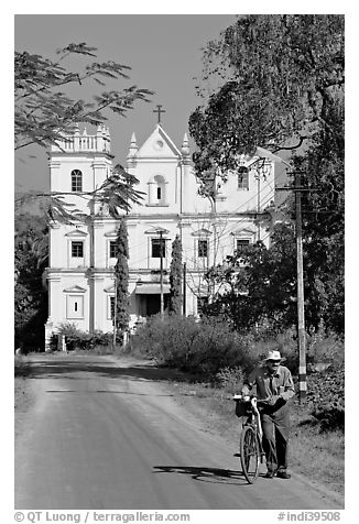 Man walking a bicycle in front of church of St John, Old Goa. Goa, India