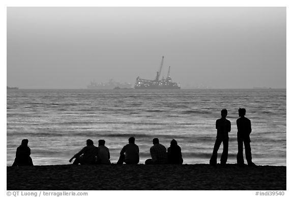 People and  off-shore platforms, Miramar Beach, sunset. Goa, India (black and white)