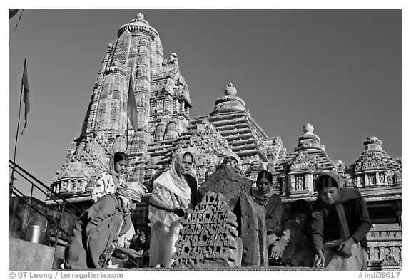 Worshippers making offering with Lakshmana temple behind. Khajuraho, Madhya Pradesh, India (black and white)