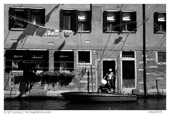 Resident stepping from his boat to his house,  Castello. Venice, Veneto, Italy (black and white)