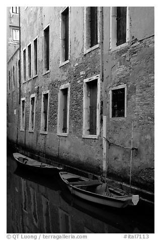 Small boats moored along a wall in a small side canal. Venice, Veneto, Italy (black and white)