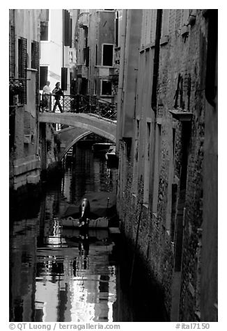 Pedestrians on a bridge over a narrow canal. Venice, Veneto, Italy