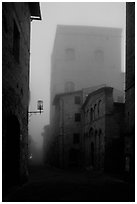 Street and medieval tower at dawn in the fog. San Gimignano, Tuscany, Italy (black and white)