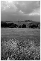 Field and distant village under storm skies. Tuscany, Italy (black and white)