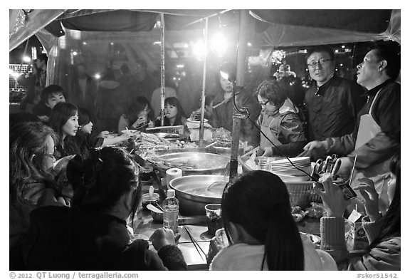 People eating noodles in a tent at night. Seoul, South Korea (black and white)