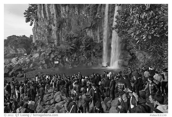 Tourists at the base of Jeongbang Pokpo falls, Seogwipo. Jeju Island, South Korea (black and white)