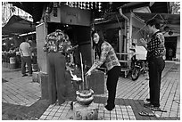 Worshiping at Buddhist street altar. George Town, Penang, Malaysia (black and white)